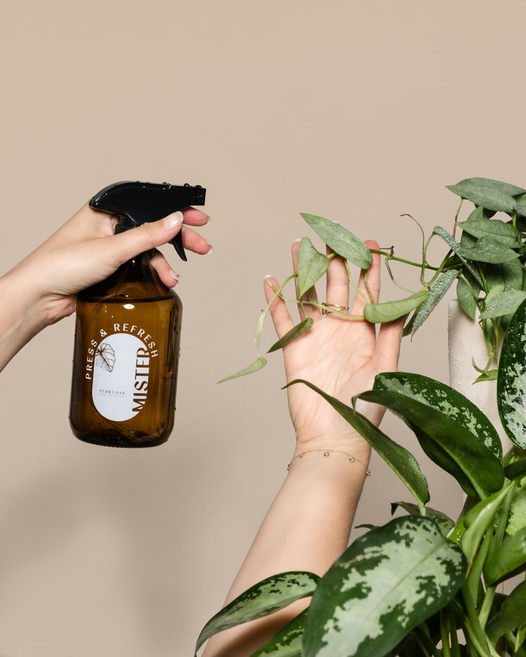 a-woman-holding-a-bottle-of-liquid-next-to-a-potted-plant-8pquwxsgnmg